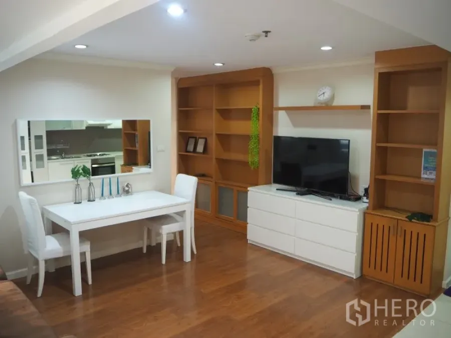 公寓 出租或出售在Watthana, Bangkok - 明亮的客餐厅，白色餐桌、木质嵌入式书架、电视柜与木地板。