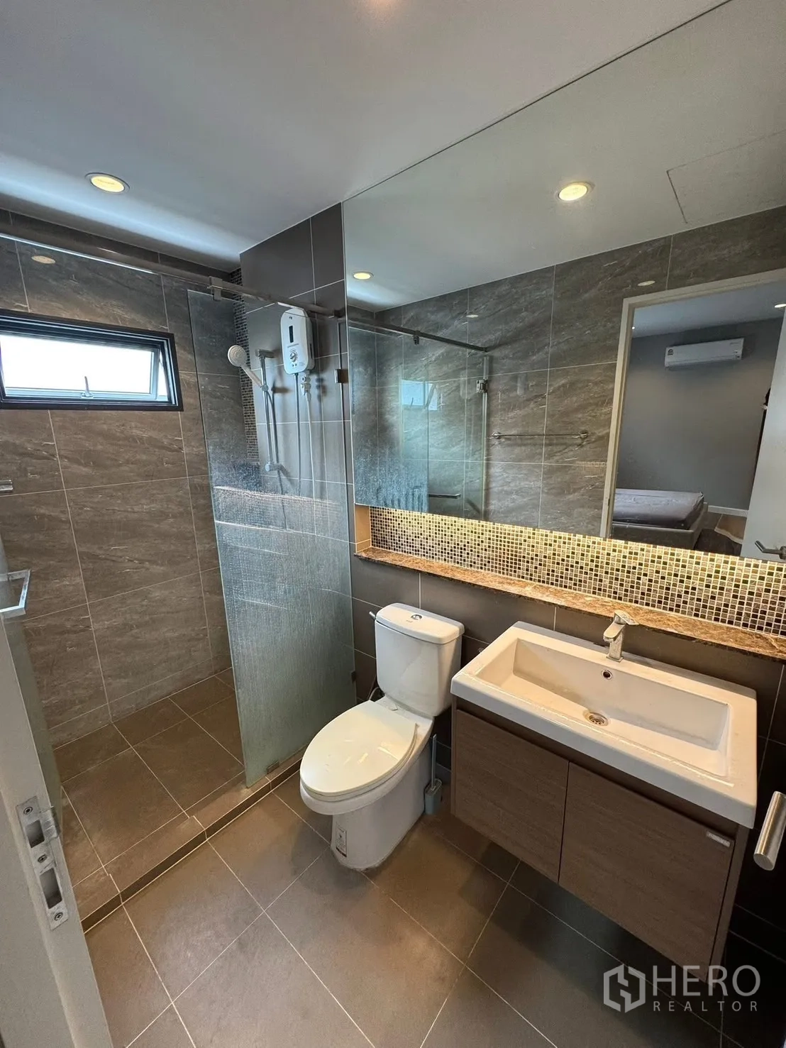 Detached House for sale in Mueang Pathum Thani, Pathum Thani - Modern bathroom with glass shower screen, vanity and wall tiles.