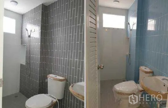 Warehouse for rent in Prawet, Bangkok - Two modern restrooms with tiled walls, showers, toilets and basins.