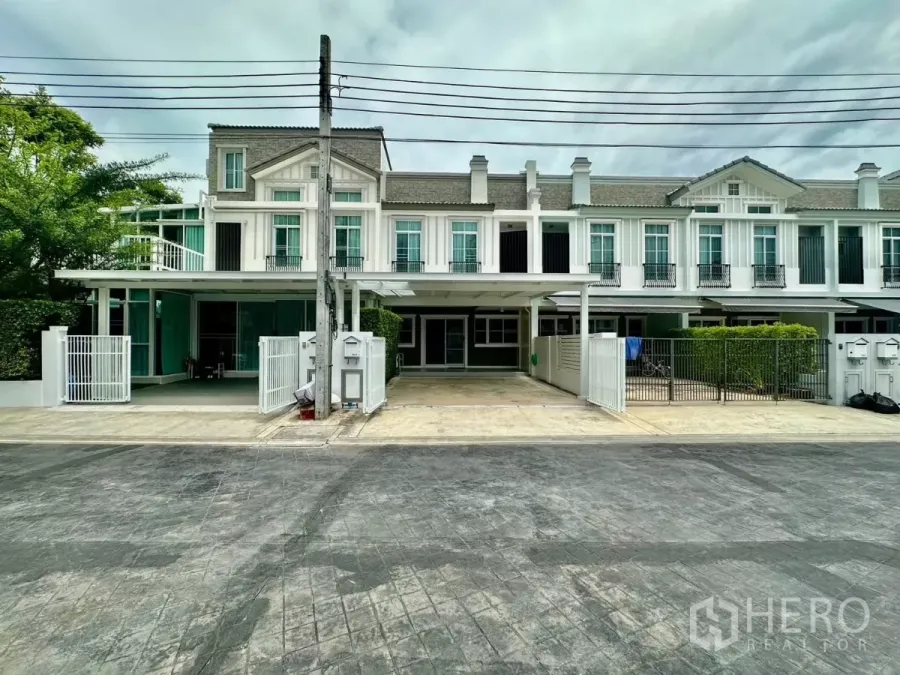 Townhouse for rent in Prawet, Bangkok - Street view of a Scandinavian-style townhouse row with white facade and small balconies.