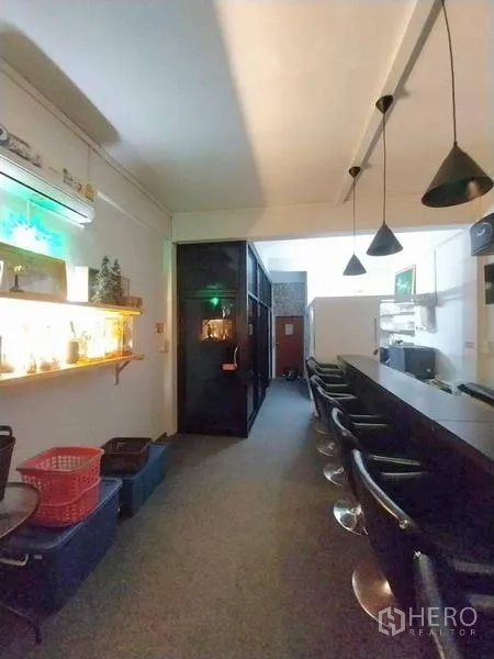 Shophouse for rent in Khlong Toei, Bangkok - Bar seating with hanging lights, glass-partitioned room and illuminated wall shelf.