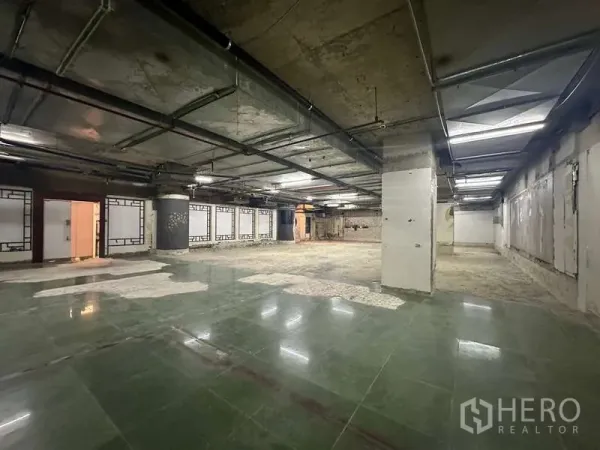 Retail Space for rent - Wide shell retail space with grid ceiling, ducts, columns and a mix of tiled and bare floors.