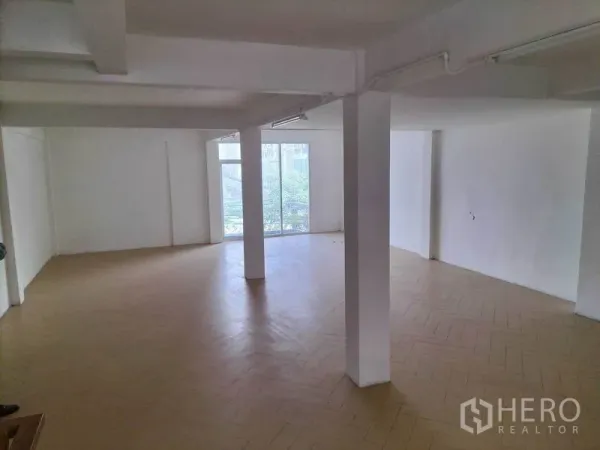 Shophouse for rent in Khlong Toei, Bangkok - Spacious level with herringbone flooring, structural columns and floor-to-ceiling windows.