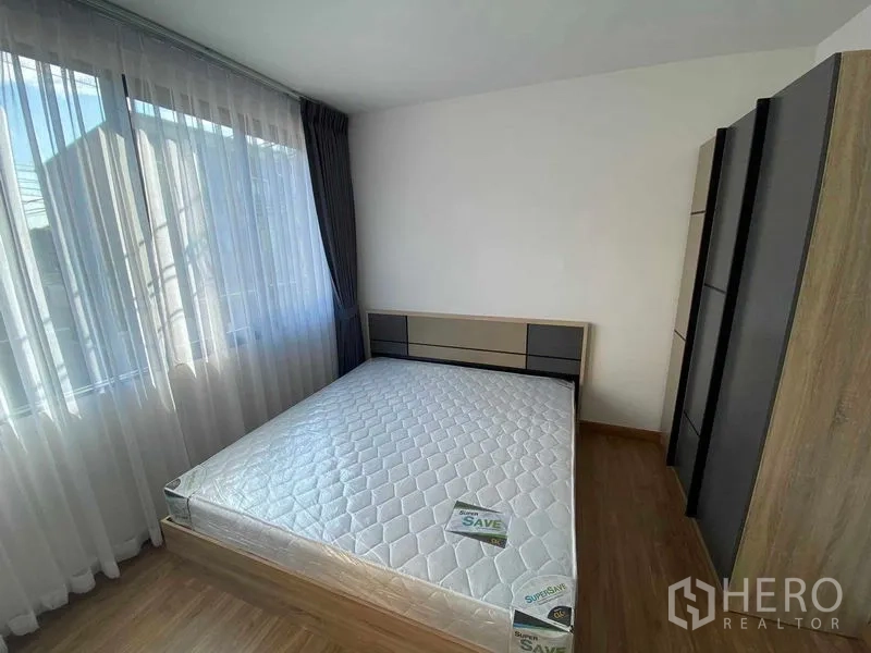 Townhouse for rent in Prawet, Bangkok - Master bedroom with large windows, sheer curtains and built-in wardrobe.
