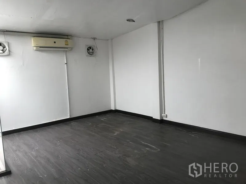 Shophouse for rent in Watthana, Bangkok - Air-conditioned room with twin wall exhaust fans and dark wood flooring.