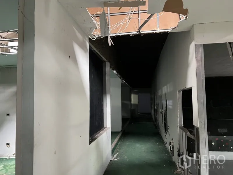Warehouse for rent in Bang Kapi, Bangkok - Service corridor with exposed cables and wall cutouts leading to warehouse rooms.