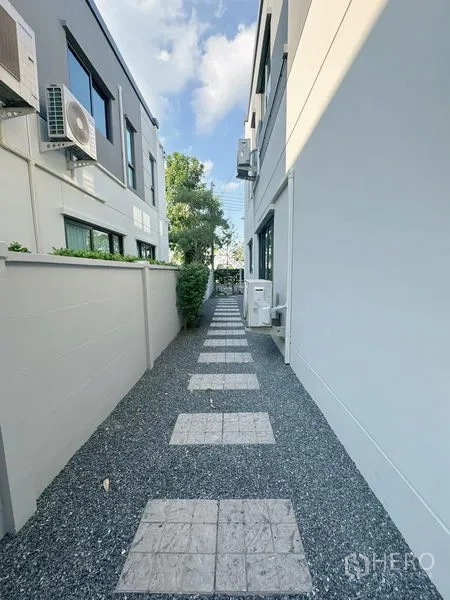 Detached House for rent or sale in Bang Phli, Samut Prakan - Gravel side path with stepping stones between neighboring houses and a privacy wall.
