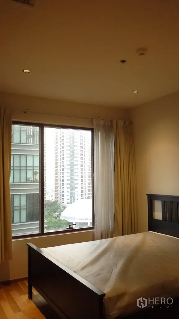 Condominium for rent in Khlong Toei, Bangkok - Second bedroom with bedframe and large window offering city views.