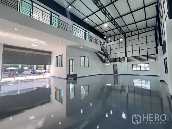 Warehouse for sale in Lam Luk Ka, Pathum Thani - High-ceiling warehouse hall with glossy epoxy floor, roller shutter and mezzanine office stair.