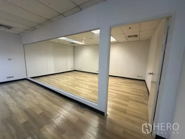 Office Space for rent in Phra Khanong, Bangkok - Glass‑partitioned meeting room with a wide mirror and hinged door, wood‑look flooring throughout.