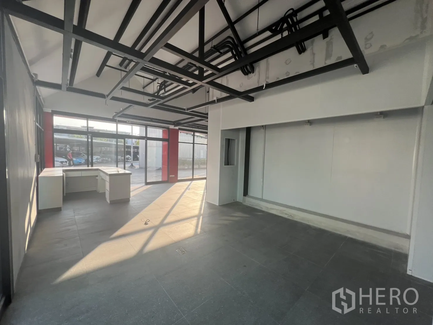 Retail Space for rent - Long retail hall with wide windows, grey tiles and visible service conduits.