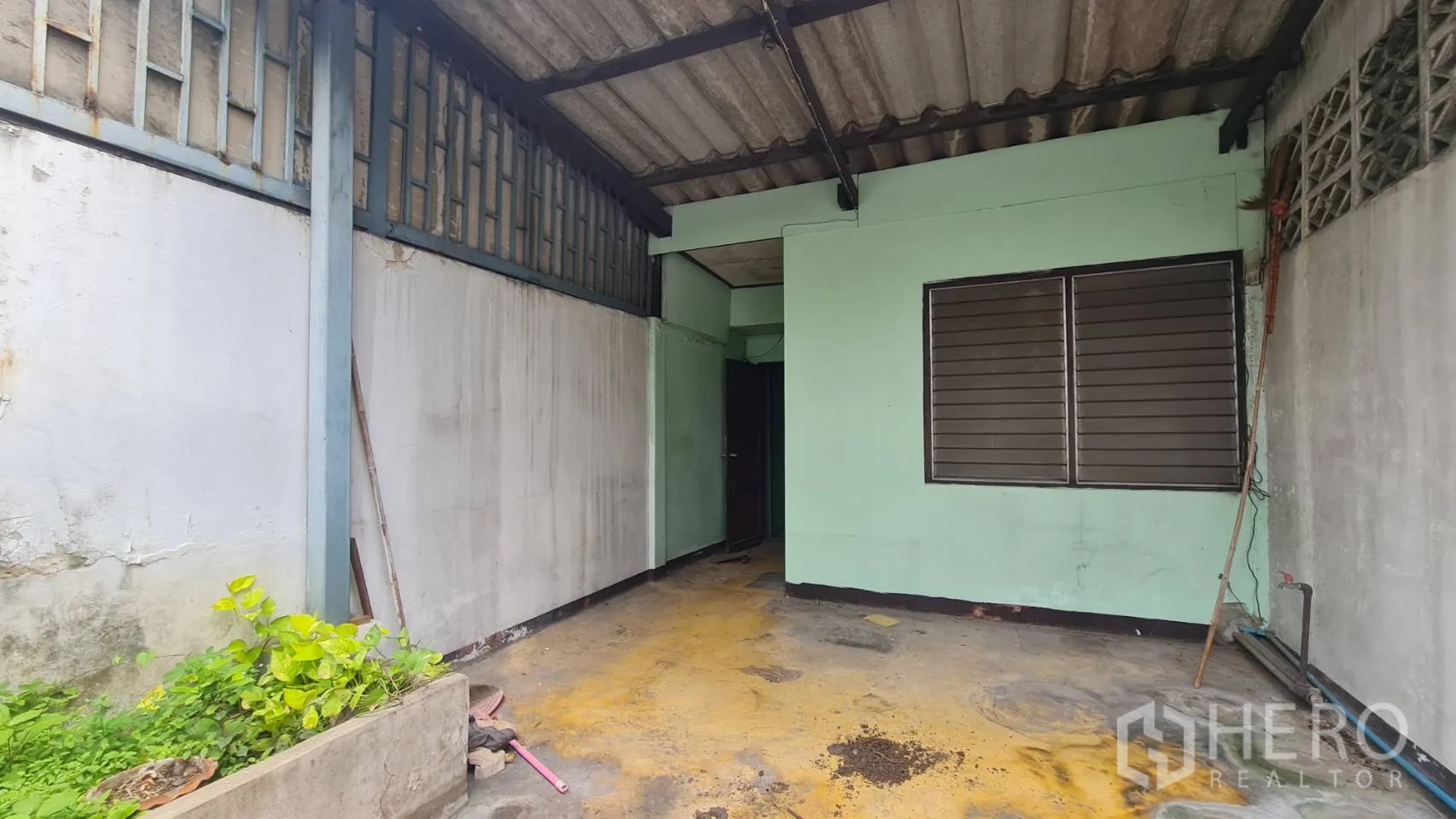 店屋 出租或出售在Watthana, Bangkok - 有顶露台，绿色外墙、百叶窗与水泥地面。