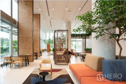 办公空间 出租在Chatuchak, Bangkok - 一层社交空间，咖啡馆式座椅与室内绿植，紧邻高窗。