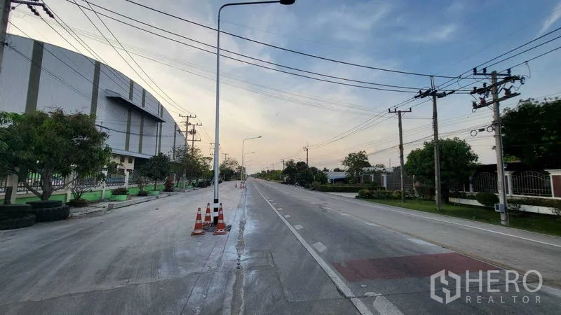 Factory for rent in Sai Noi, Nonthaburi - Two‑lane road with streetlights and power lines in front of the factory for easy truck access.