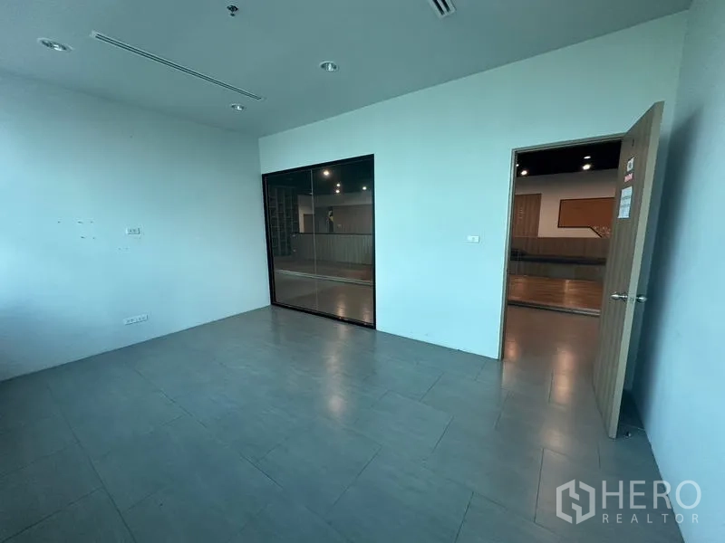 Office Space for rent in Ratchathewi, Bangkok - Bright private office with tiled floor and internal glass window overlooking corridor.