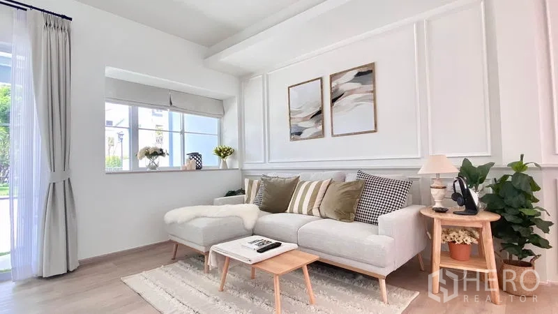Townhouse for rent in Prawet, Bangkok - Cozy living corner with L-shaped sofa, rug, decorative wall panels and garden views.