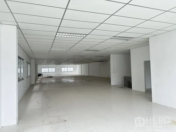 工厂 出租在Pathum Thani - 工厂内宽敞的白色办公楼层，格栅吊顶与窗户。