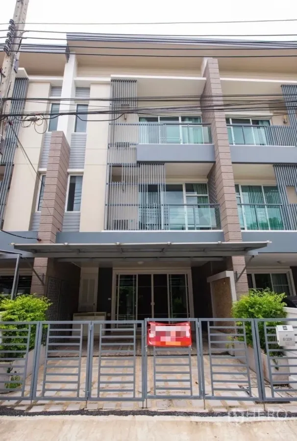 Townhouse for rent in Suan Luang, Bangkok - Contemporary three-storey townhouse exterior with balconies and a gated covered carport in Suan Luang, Bangkok.