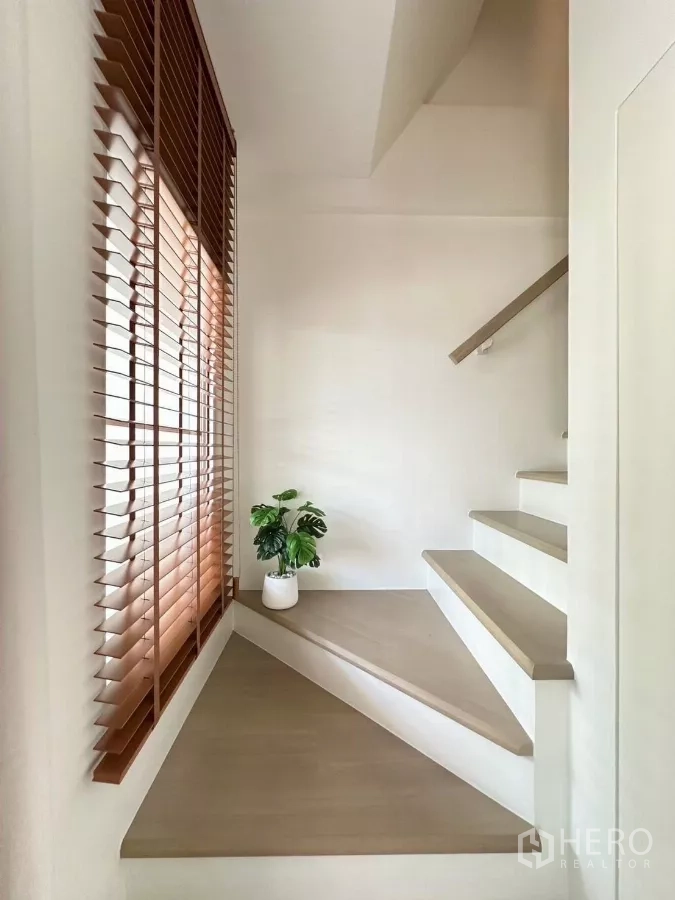 Townhouse for rent in Prawet, Bangkok - Stairwell landing with wooden blinds, triangular platform and potted plant.