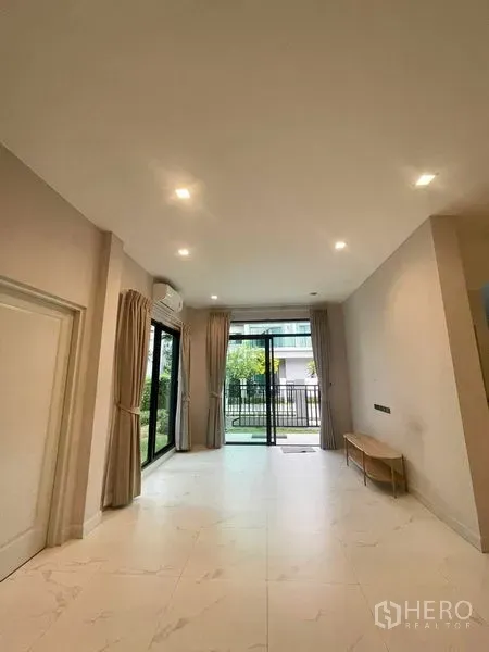 Detached House for sale in Bang Kruai, Nonthaburi - Ground‑floor living area with large sliding glass doors to the garden, recessed lights and tile flooring.