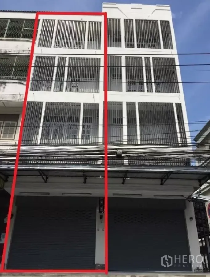 Shophouse for rent in Suan Luang, Bangkok - Front facade of a four-storey white shophouse with metal shutters and vertical grills in the On Nut area.