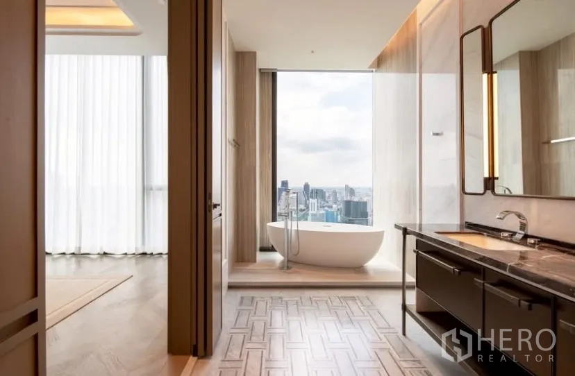 Condominium for rent or sale in Pathum Wan, Bangkok - Master bathroom featuring a freestanding soaking tub by a picture window with city skyline.