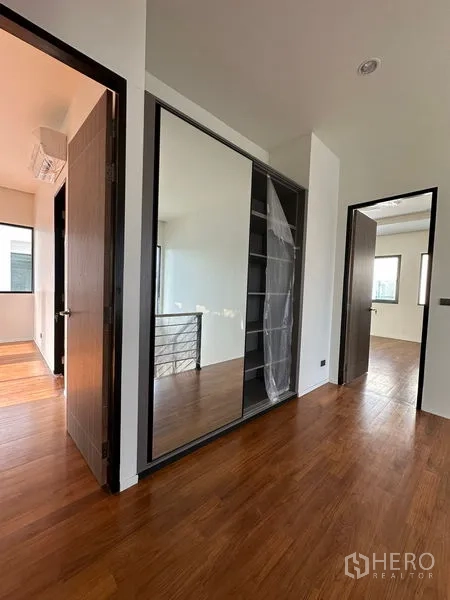 Detached House for rent in Watthana, Bangkok - Upstairs landing with built-in mirrored closet and wood floors connecting to bedrooms.