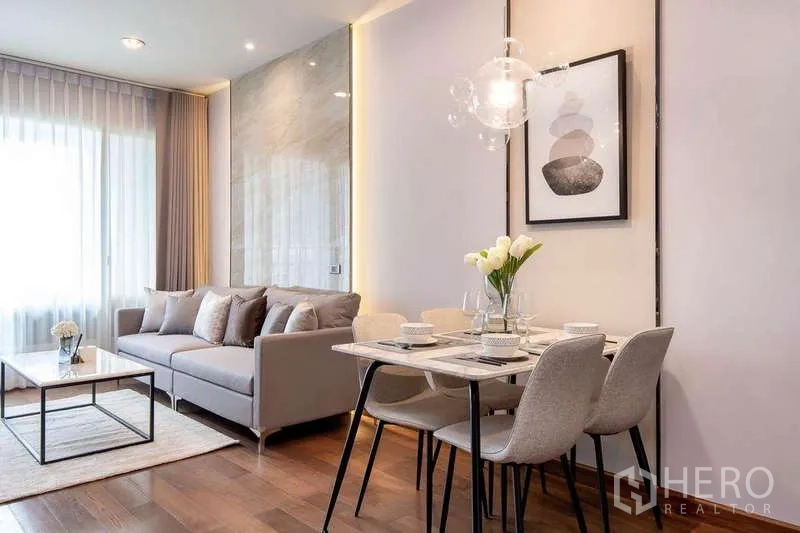 Condominium for rent in Pathum Wan, Bangkok - Cozy dining corner with pendant light beside sofa and accent wall.