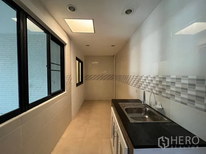 Townhouse for rent or sale in Khlong Toei, Bangkok - Fitted Thai kitchen with dual sink, tiled walls and mosaic backsplash.