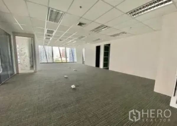 Office Space for rent - Open-plan office with carpet tiles, drop ceiling lighting and corner windows providing natural light.