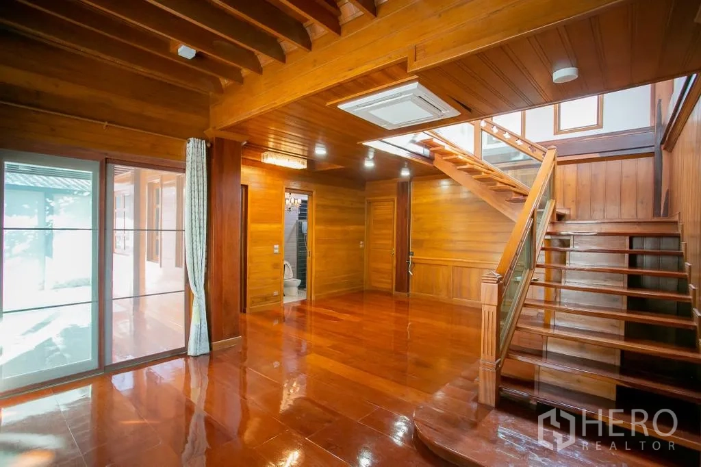 Detached House for rent or sale in Huai Khwang, Bangkok - Living room angle showing staircase, sliding glass doors and nearby bathroom.