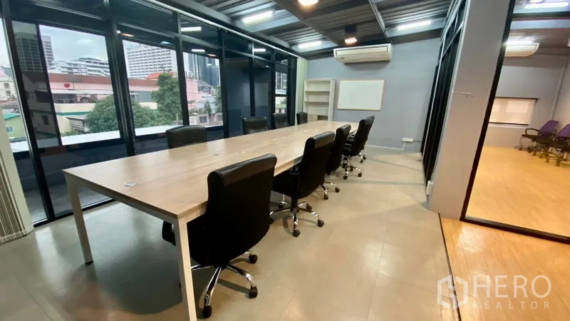 Office Space for rent in Sathon, Bangkok - Boardroom with long table, black chairs, large windows, and wall-mounted air conditioner.