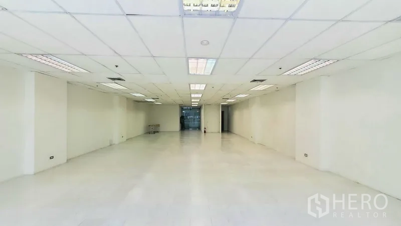 Office Space for rent in Khlong Toei, Bangkok - Deep rectangular office space with tiled floors and a glass entry at the far end.