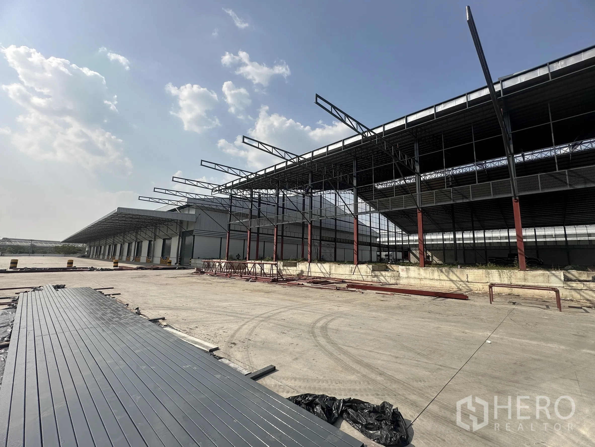 工厂 for rent in Si Racha, Chon Buri - 钢结构厂房外观，长条雨棚装卸平台与宽阔混凝土作业场。