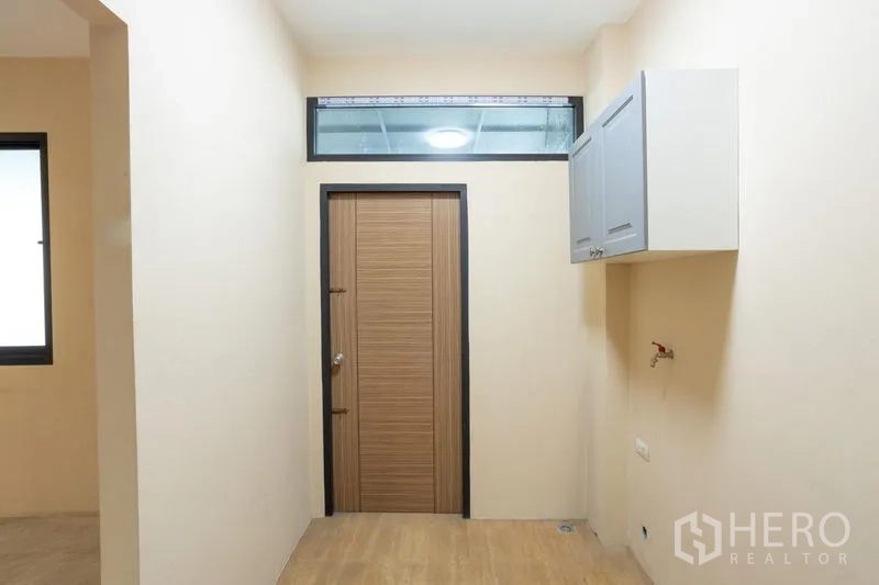 Home Office for rent in Bang Khen, Bangkok - Compact utility room with upper cabinet, wood door and plumbing ready for washer.