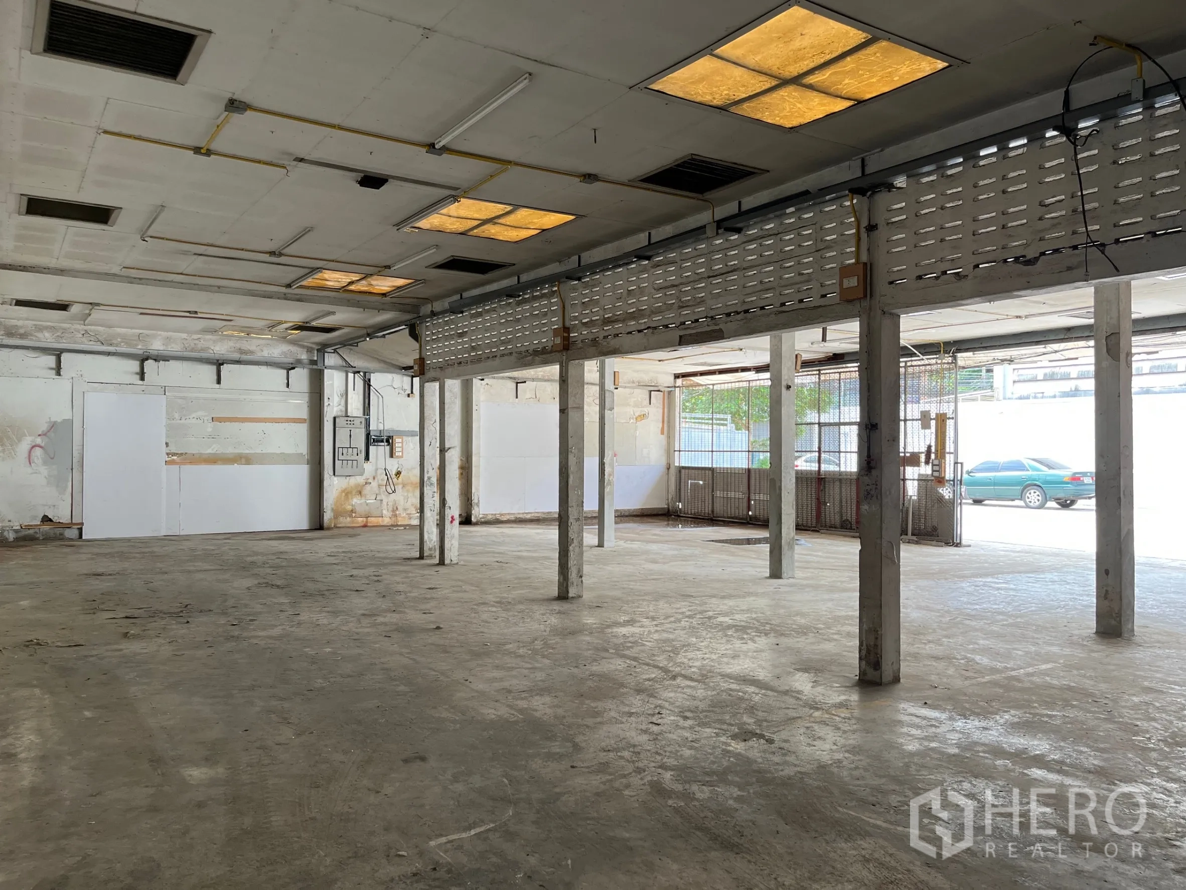 Warehouse for rent in Bangkok - Warehouse interior near loading entry with fluorescent lighting and open layout.