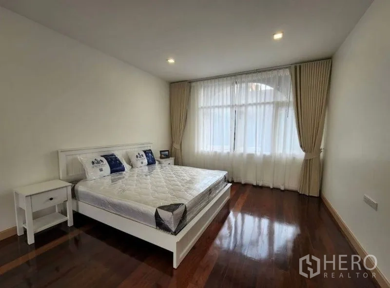 Townhouse for sale - Primary bedroom with large window, white bed frame and polished wood floors.