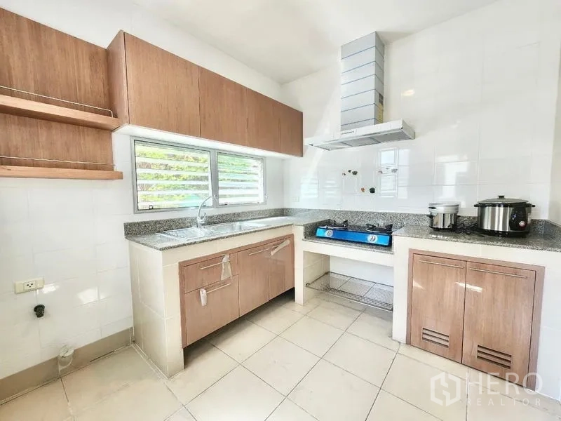 Detached House for rent in Prawet, Bangkok - Separate Thai kitchen with wood cabinets, window, hob, hood and granite counters.