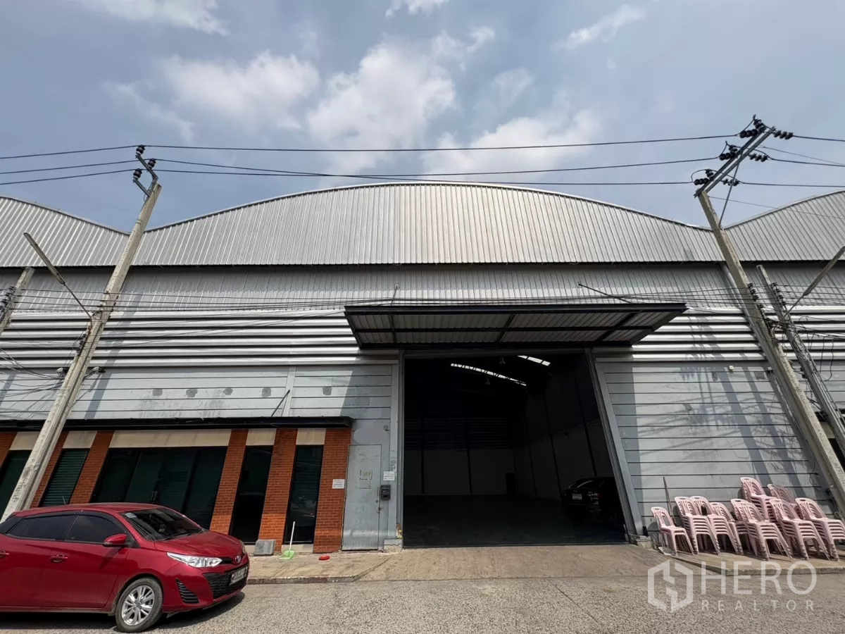 Warehouse for rent in Bang Phli, Samut Prakan - Street-side view of metal-clad warehouse facade with large roller shutter and parking in Bang Phli.