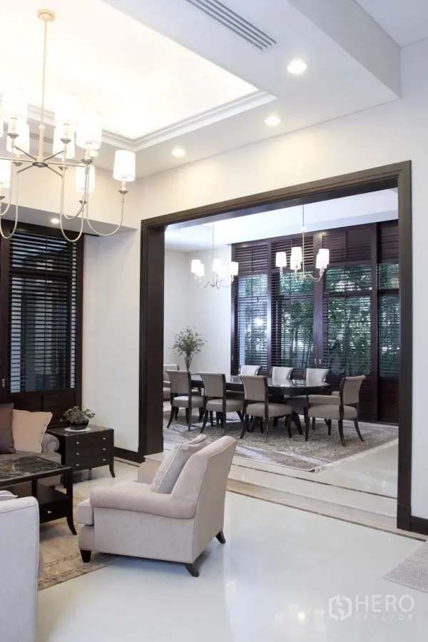Detached House for rent in Khlong Toei, Bangkok - Bright living area opening to a formal dining room with chandeliers, dark wood trim and large window shutters.