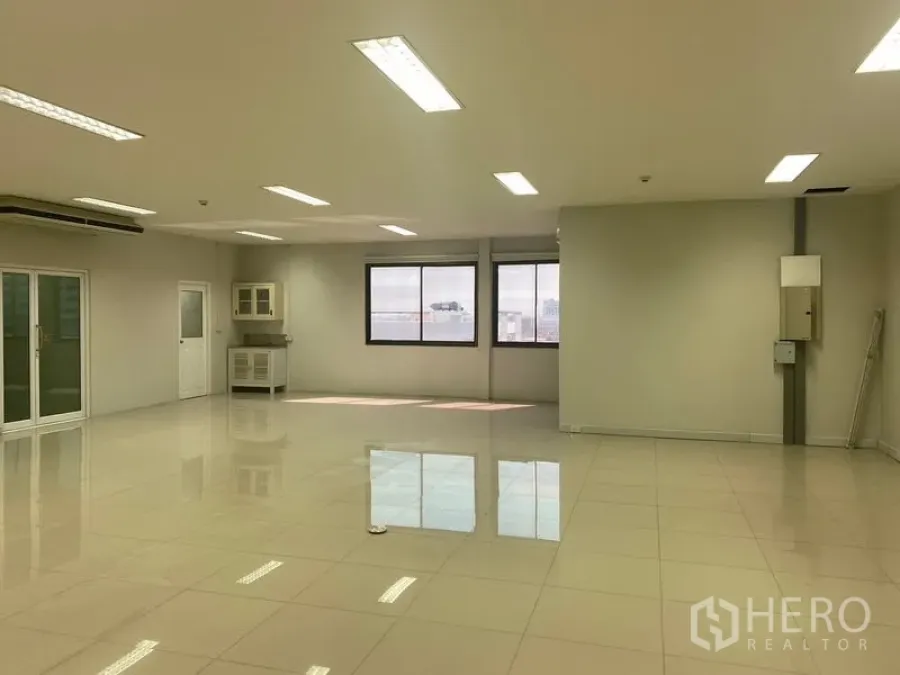 Office Space for rent in Bang Na, Bangkok - Open-plan office with city-view windows, a corner pantry and bright ceiling lights.