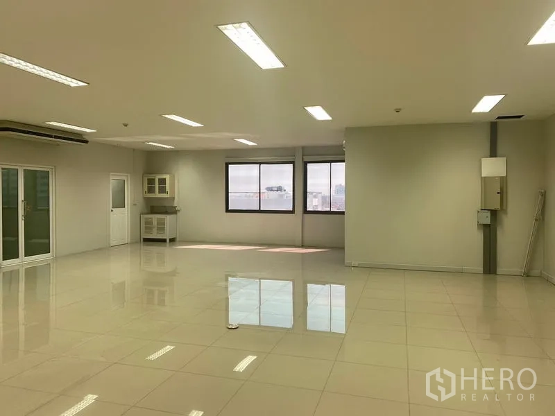 Office Space for rent in Bang Na, Bangkok - Open-plan office with city-view windows, a corner pantry and bright ceiling lights.