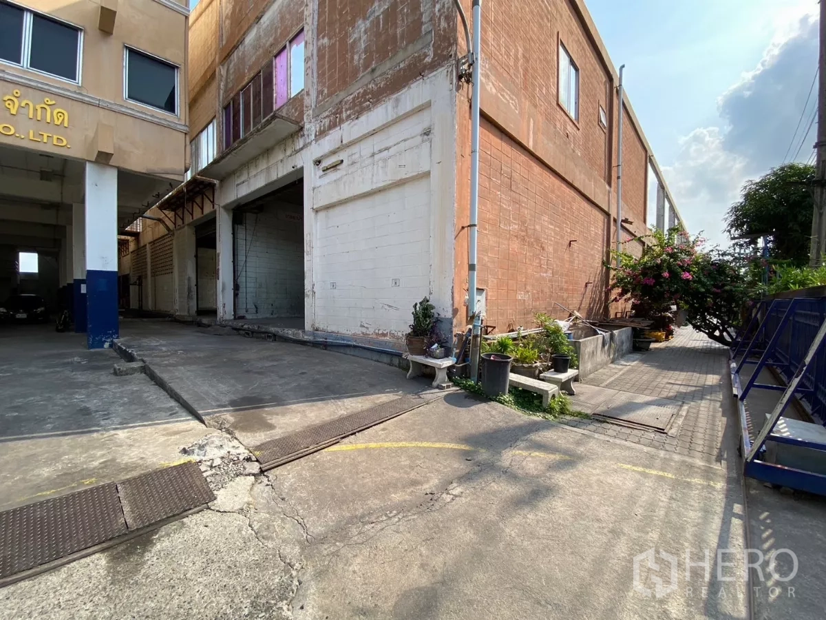 工厂 出售在Bang Phli, Samut Prakan - 装卸区位于红砖厂房旁，靠近车道，摆放小型花盆。
