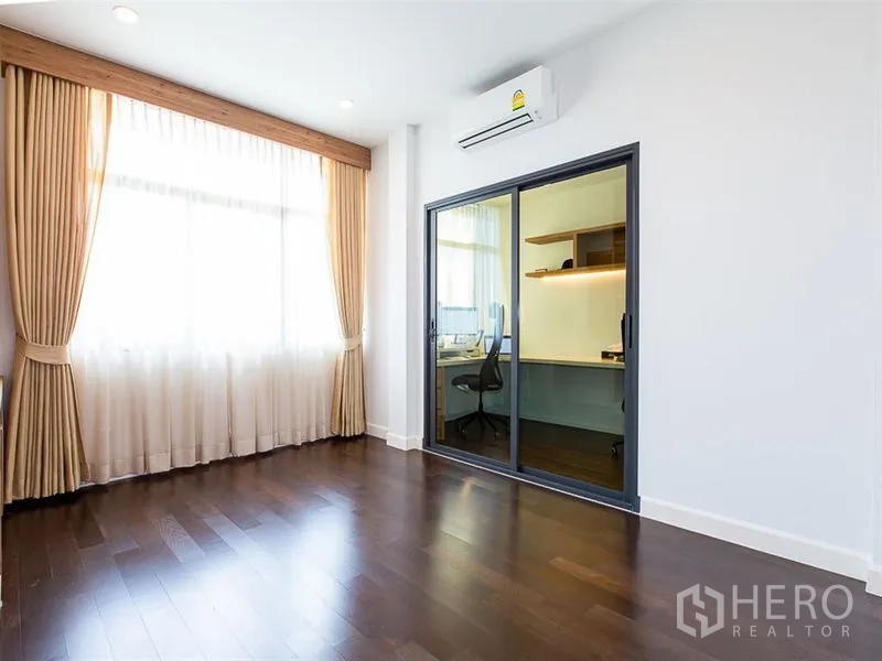 Detached House for rent or sale in Prawet, Bangkok - Sunlit bedroom with sliding glass door opening to a built-in home office.