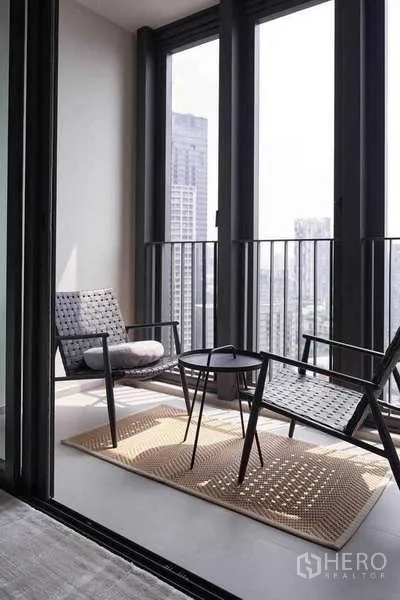 Condominium for rent or sale in Khlong Toei, Bangkok - Balcony seating area with two chairs and side table overlooking high-rise views.