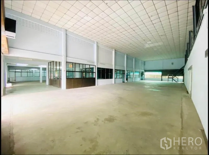 Factory for rent in Sam Phran, Nakhon Pathom - High-ceiling production hall with concrete floor and windowed partition offices along one side.