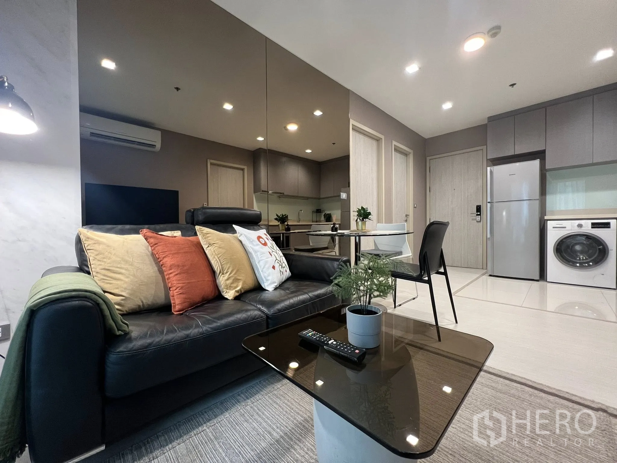 Condominium for rent in Khlong Toei, Bangkok - Open-plan lounge with leather sofa, coffee table, round dining table, and glossy tile floors.