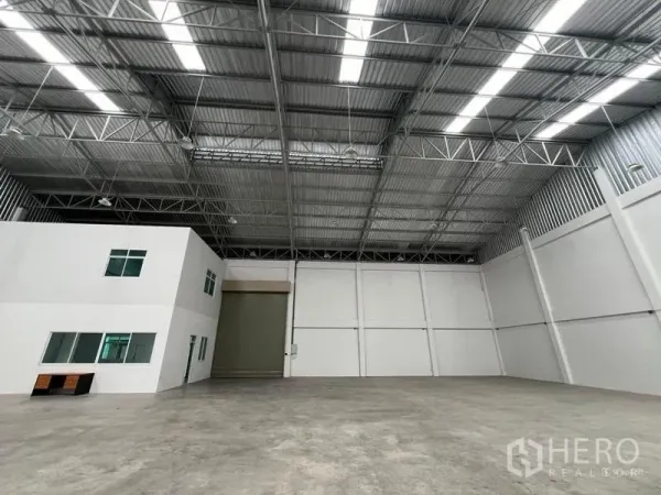 Factory for rent in Phra Samut Chedi, Samut Prakan - High-clearance production hall with steel truss roof, skylights, concrete floor and wide loading shutter.