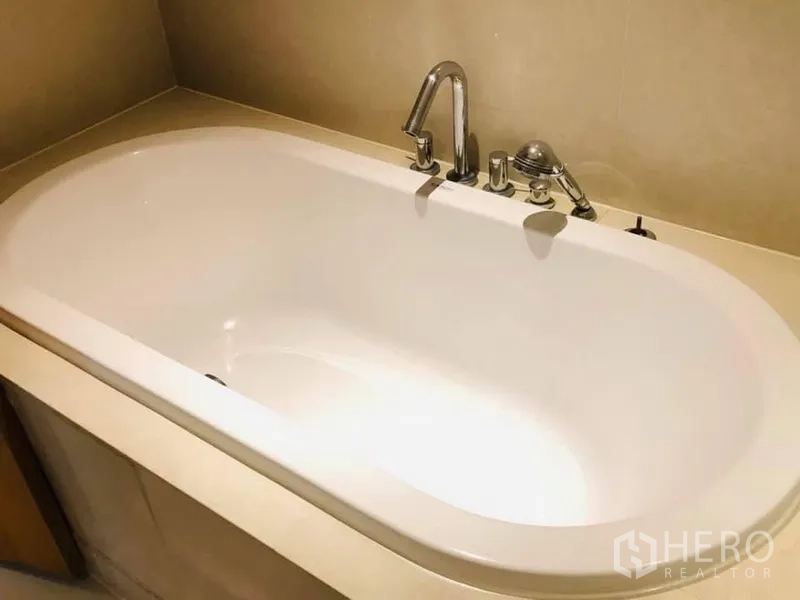 Condominium for rent in Khlong Toei, Bangkok - Modern white bathtub with chrome fixtures in a contemporary Khlong Toei, Bangkok condominium.