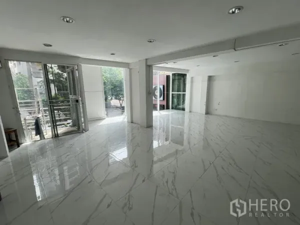 Retail Space for rent in Khlong Toei, Bangkok - Bright open-plan retail interior with large windows and glossy marble-look tiles opening to a small terrace.
